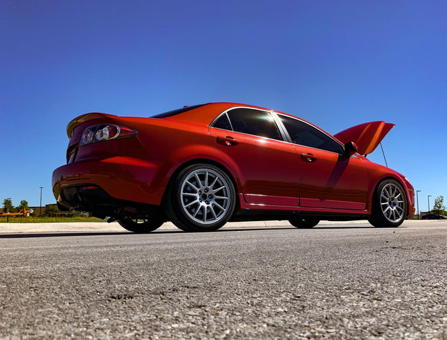 Red Mazdaspeed6 with its hood open, photographed from the rear quarter.