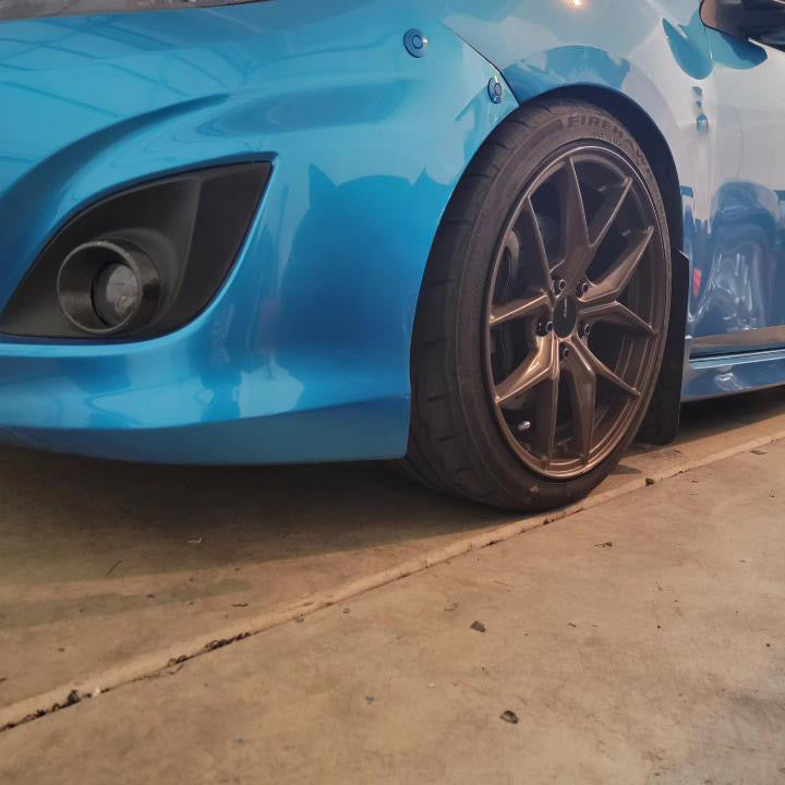 Two black bumper latches installed beside the front wheel of a blue second-generation Mazdaspeed3.