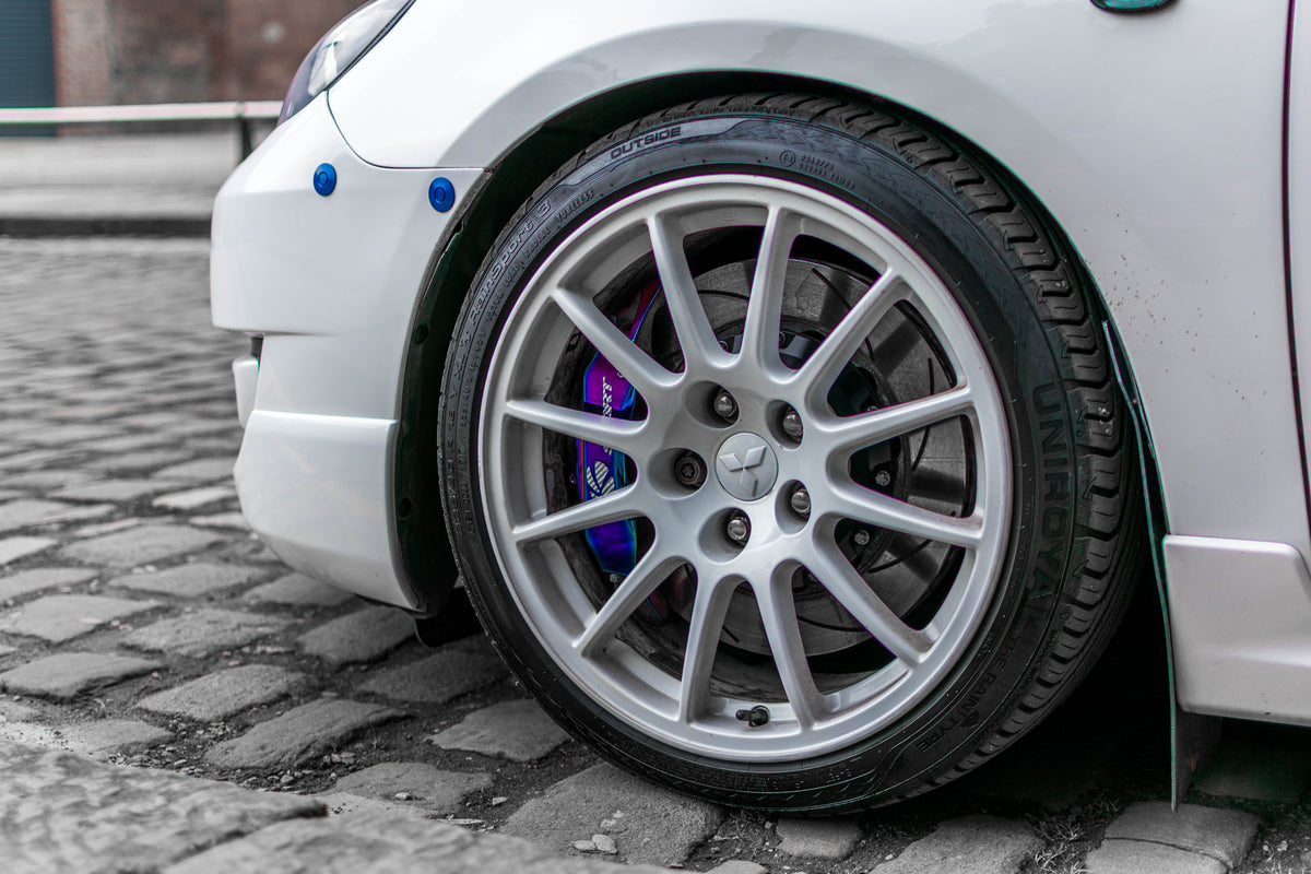Two blue latches installed along the front bumper seam of a silver first-generation Mazdaspeed3.