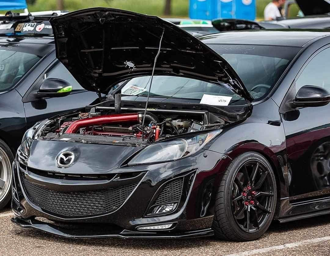 Black second-generation Mazdaspeed3 with the front bumper and open engine bay in view.