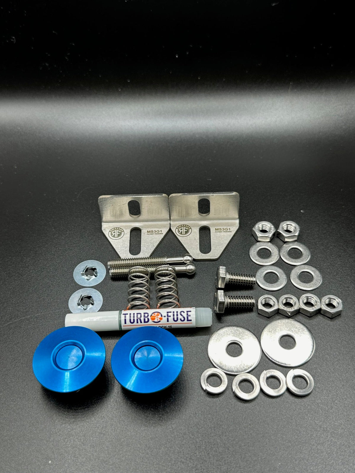 RaiderFab first-generation Mazda3 fenderwell kit with two blue latches, brackets, threadlocker and hardware.