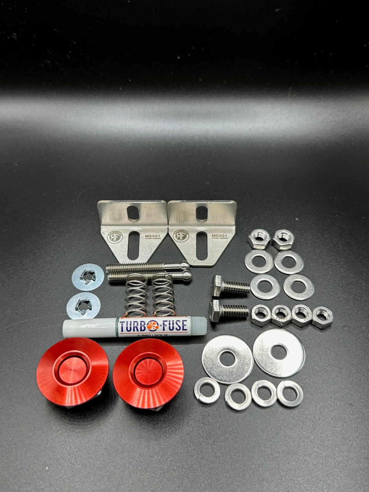 RaiderFab first-generation Mazda3 fenderwell kit with two red latches, brackets, threadlocker and hardware.