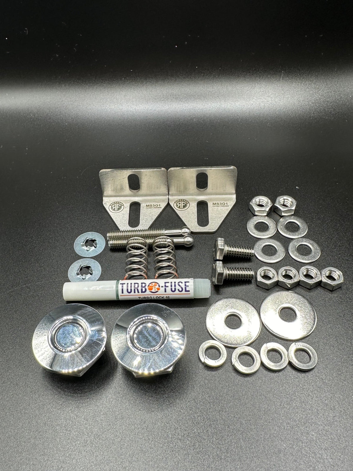 RaiderFab first-generation Mazda3 fenderwell kit with two polished latches, brackets, threadlocker and hardware.