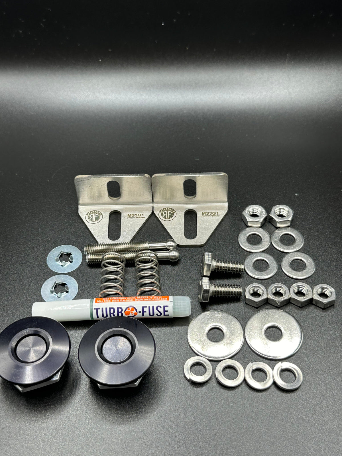 RaiderFab first-generation Mazda3 fenderwell kit with two black latches, brackets, threadlocker and hardware.