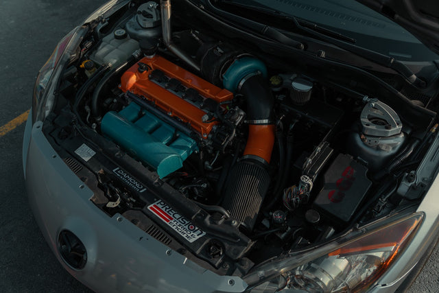 Mazdaspeed3 engine bay with an orange valve cover and turquoise intake manifold.