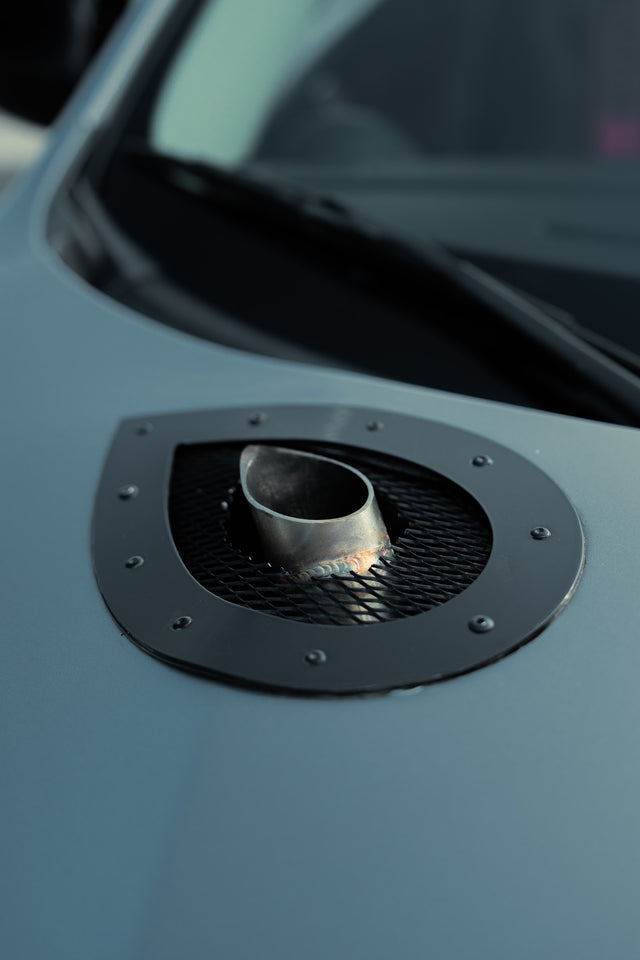Metal wastegate outlet through a circular opening in the Mazdaspeed3 hood.